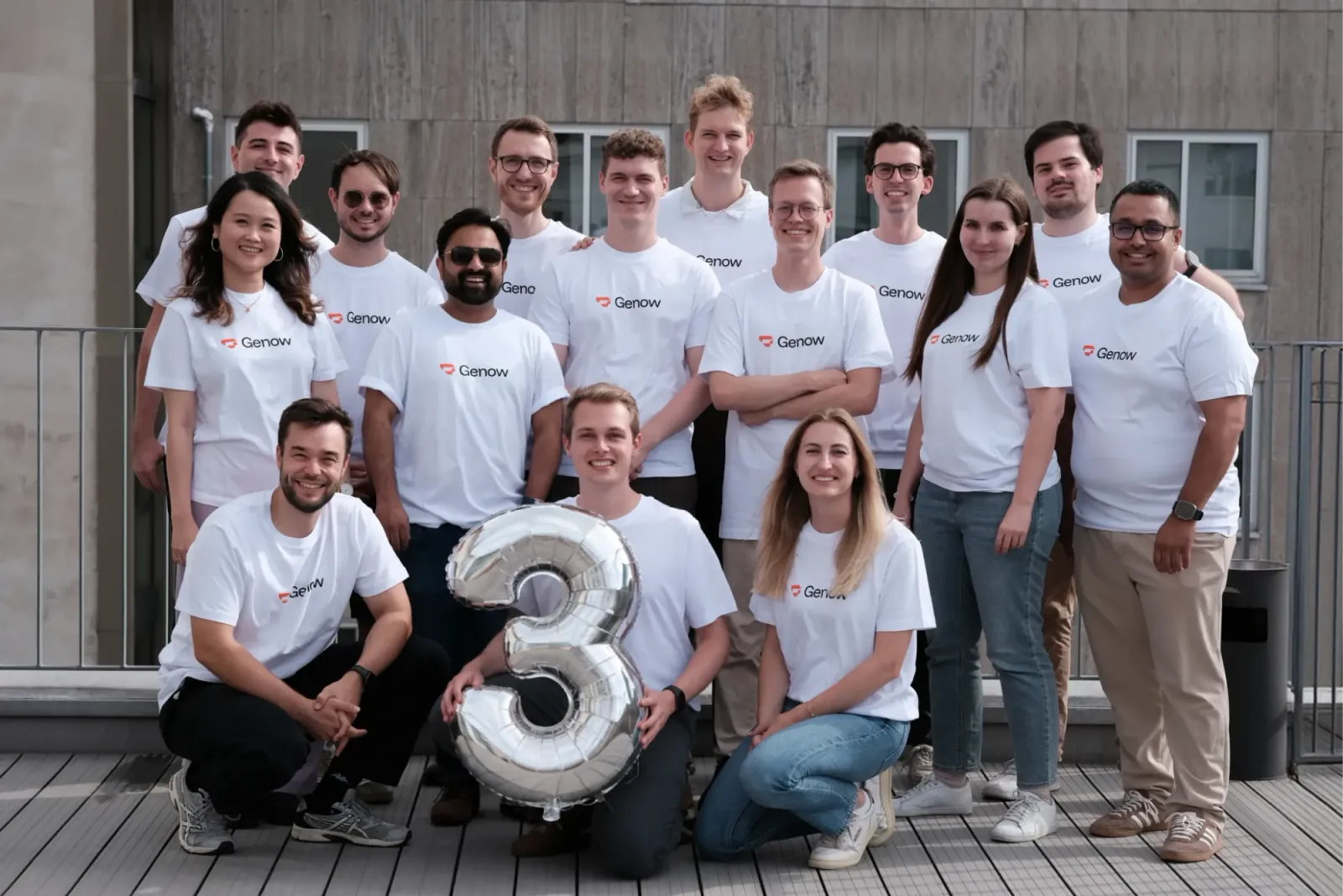 Group photo of the Genow team on the office roof terrace with a balloon shaped like a three for the company's third anniversary